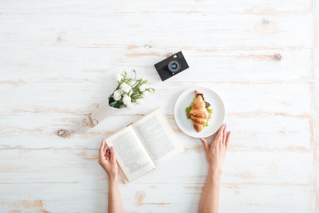 female hands holding book on the wooden desk